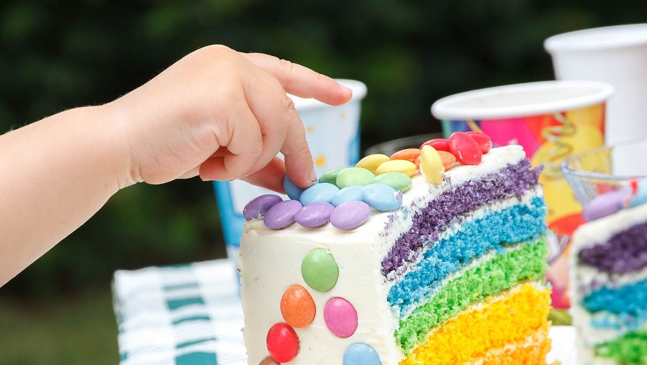 Hand greift nach Schokolinse auf einer Torte