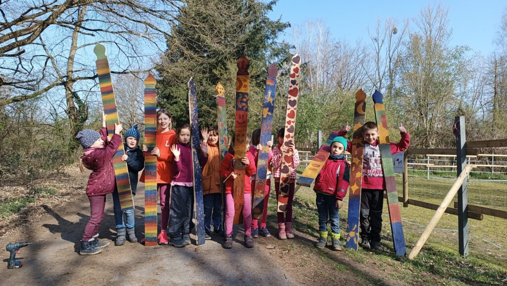 Kinder zeigen bemalte Zaunpfosten in den Ferienspielen