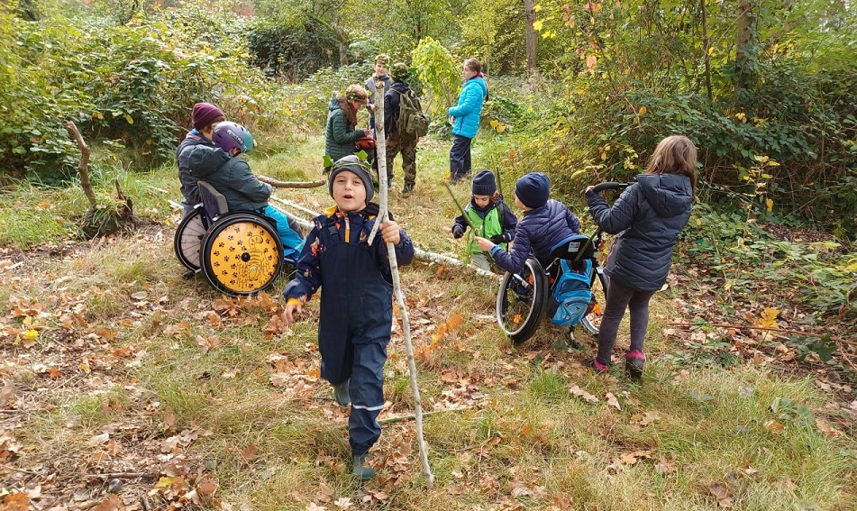 inklusive Ferienspiele - Kinder, auch Rollstuhlfahrer - spielen auf einer Wiese