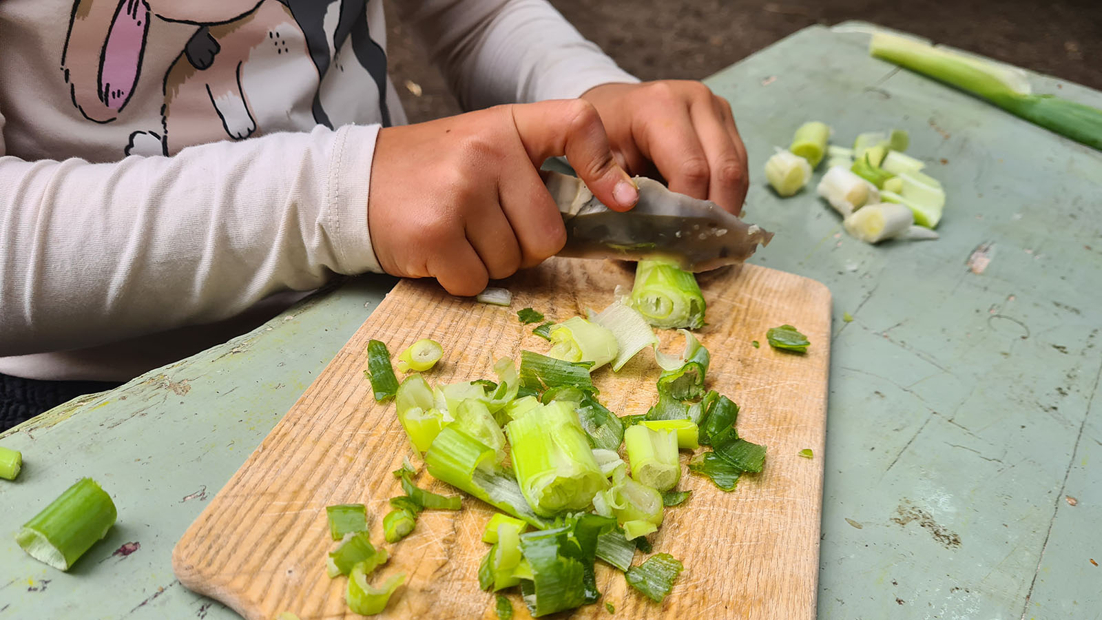 Kind schneidet Lauch mit einem Feuerstein